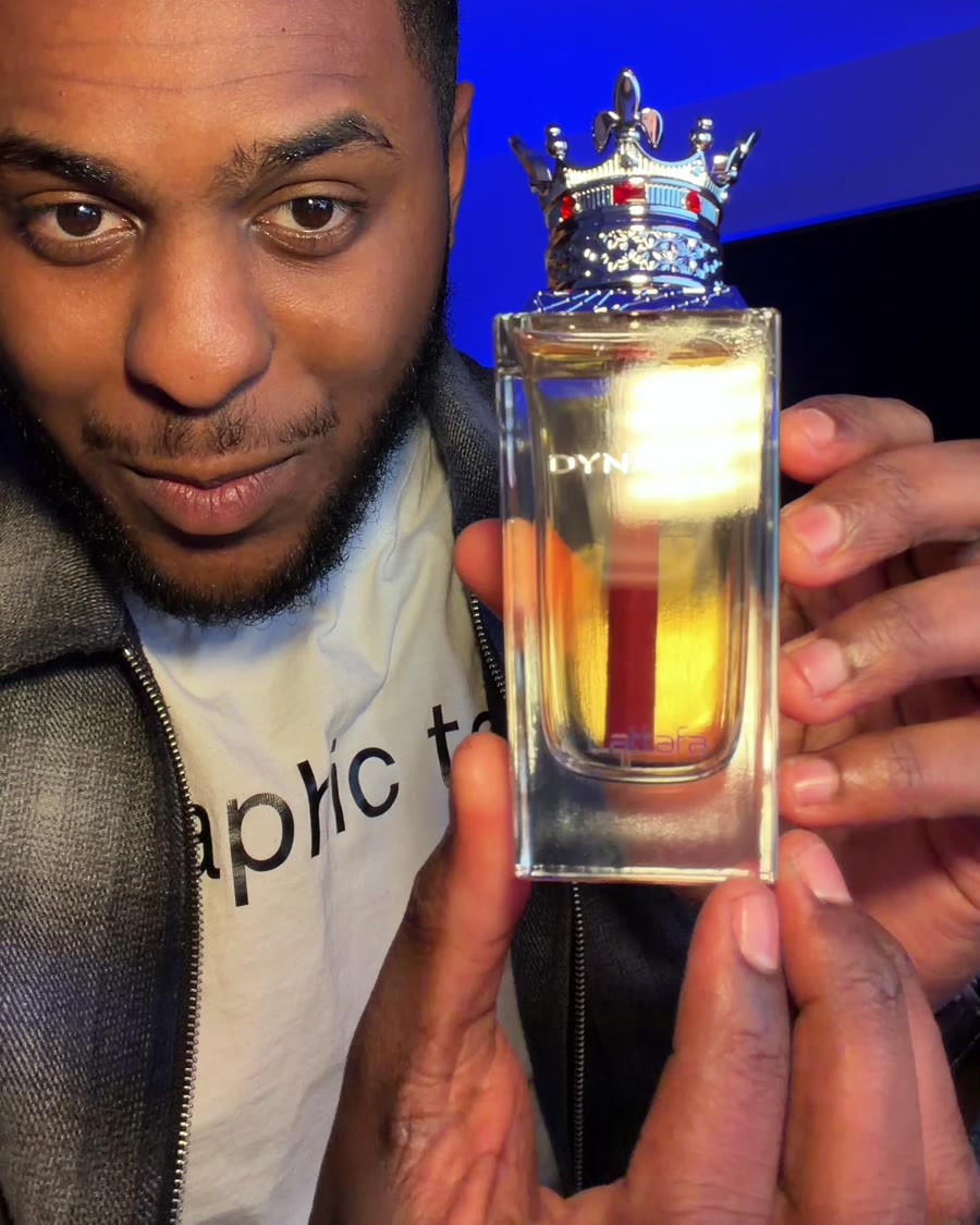Zazi holding up a crown-topped bottle of Dynasty fragrance