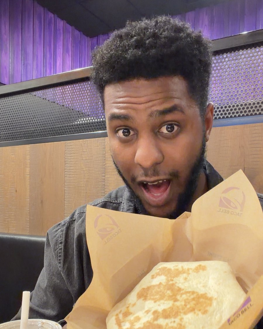 Zazi holding up the Crispy Chicken Crunchwrap at Taco Bell, eyes wide